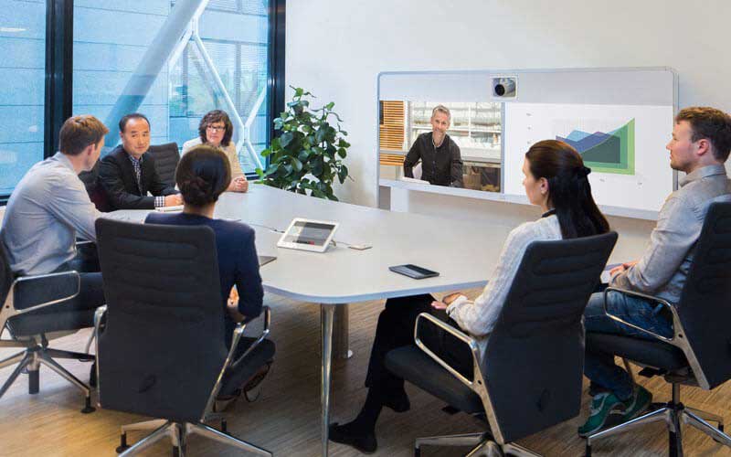 Team meeting around table using video conferencing solutions