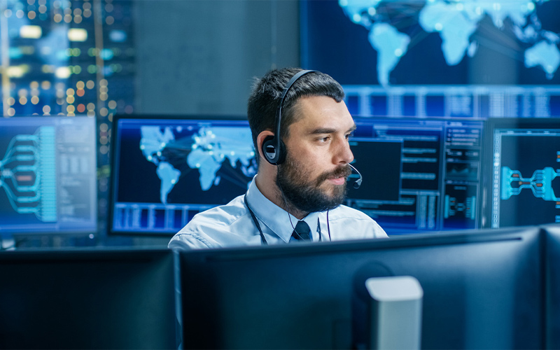 Man with headset looking at monitors