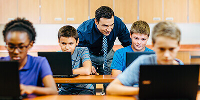 Teacher leading classroom with multiple computer devices
