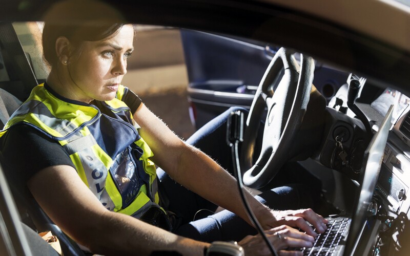 Female officer checks information through system in police car