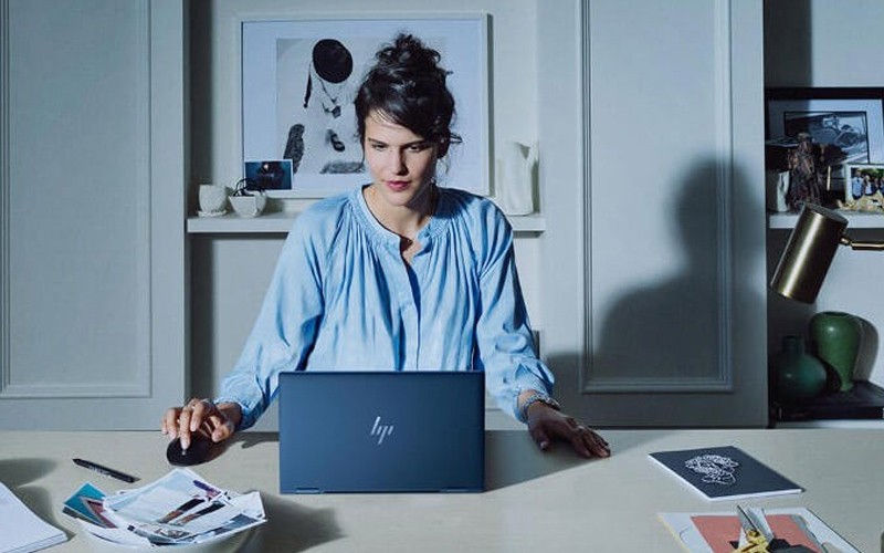 Woman sat at desk HP laptop device 