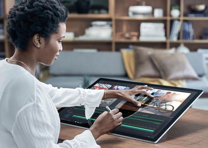 Female designer using the touch screen and Surface Pen with the drafting table display of Microsoft Surface Studio to edit video