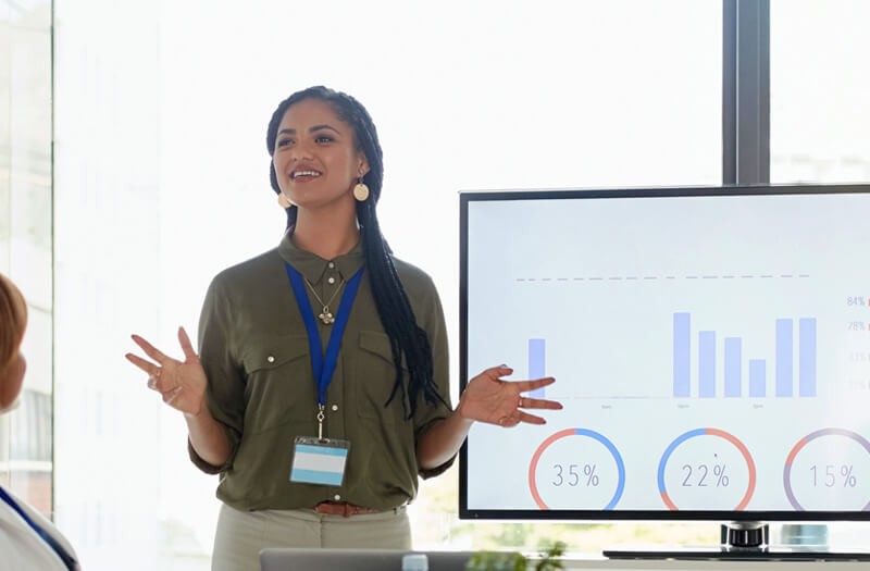 Business woman presenting in front of large flat panel monitor