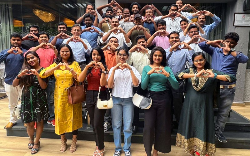 Group of business professionals from Insight India holding up heart symbols with hands