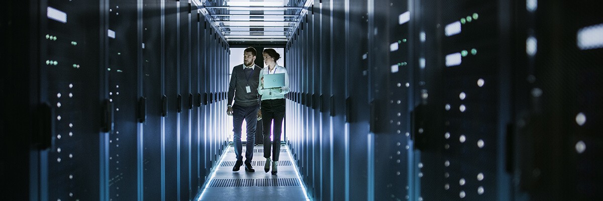 A business man and woman are walking through a server room.