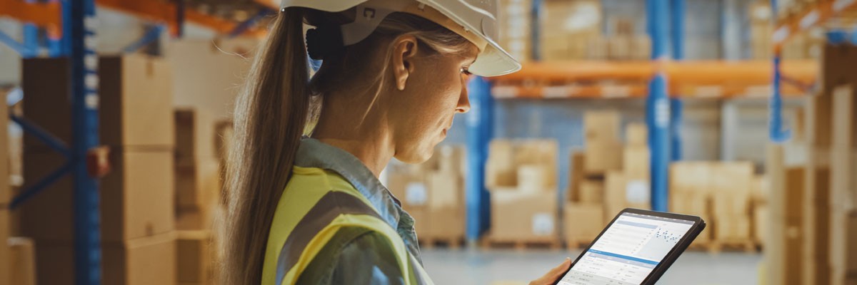 Woman in hard hat with tablet in wholesale food manufacturing warehouse