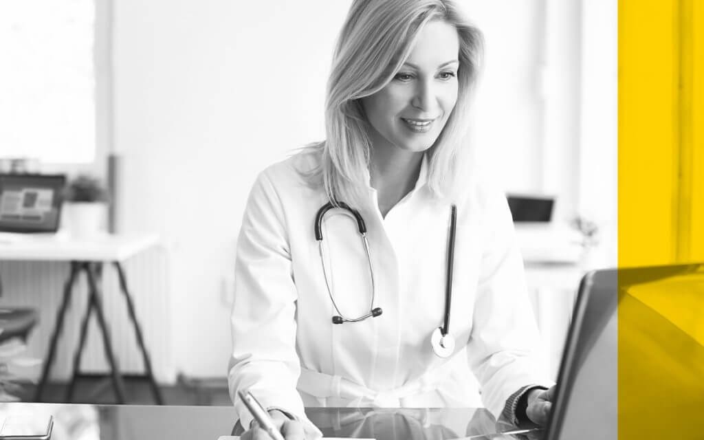 Female doctor reviews patient data on desktop computer