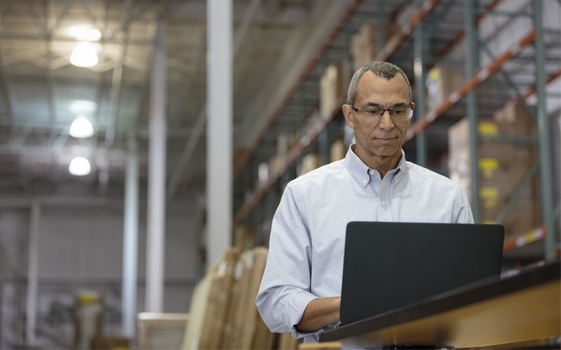 Business man working on laptop in warehouse