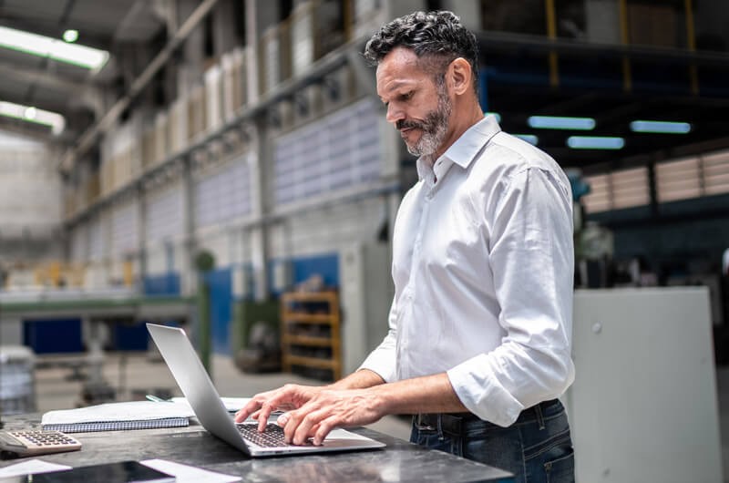 Small businessman using laptop in modern factory
