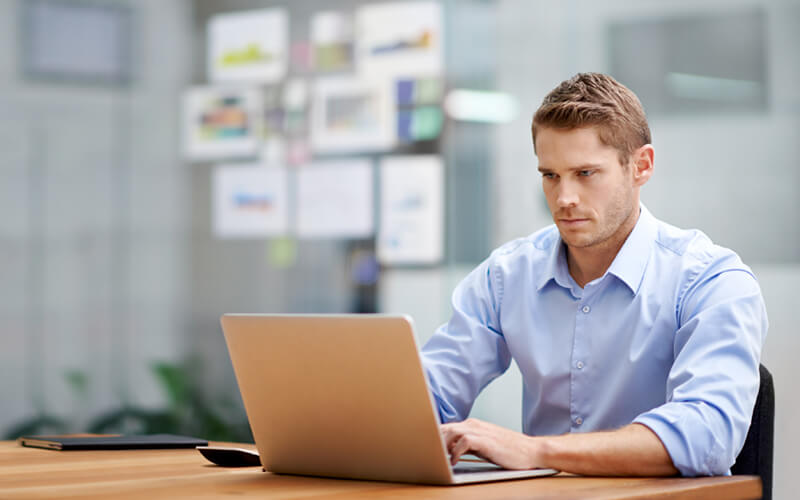 Businessman on laptop computer in bright open office space