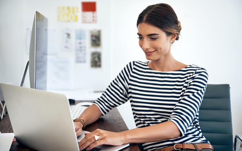 Smiling woman on laptop computer in open office