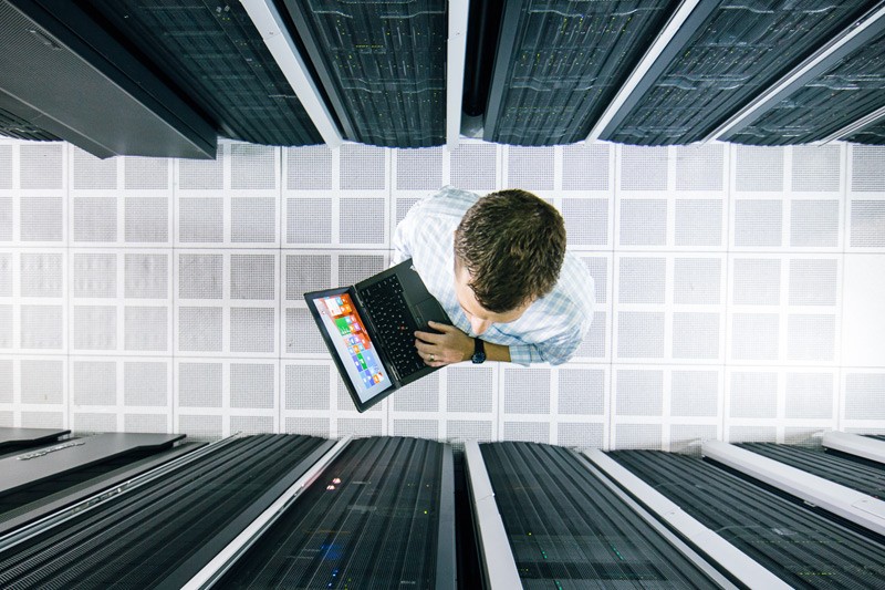 Birds eye view of an IT administrator in data center holding laptop.