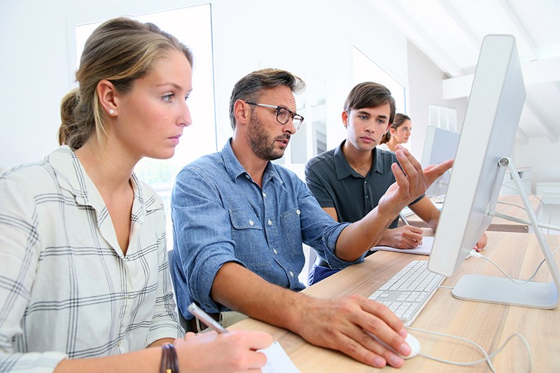 Teacher reviewing a students work on desktop computer